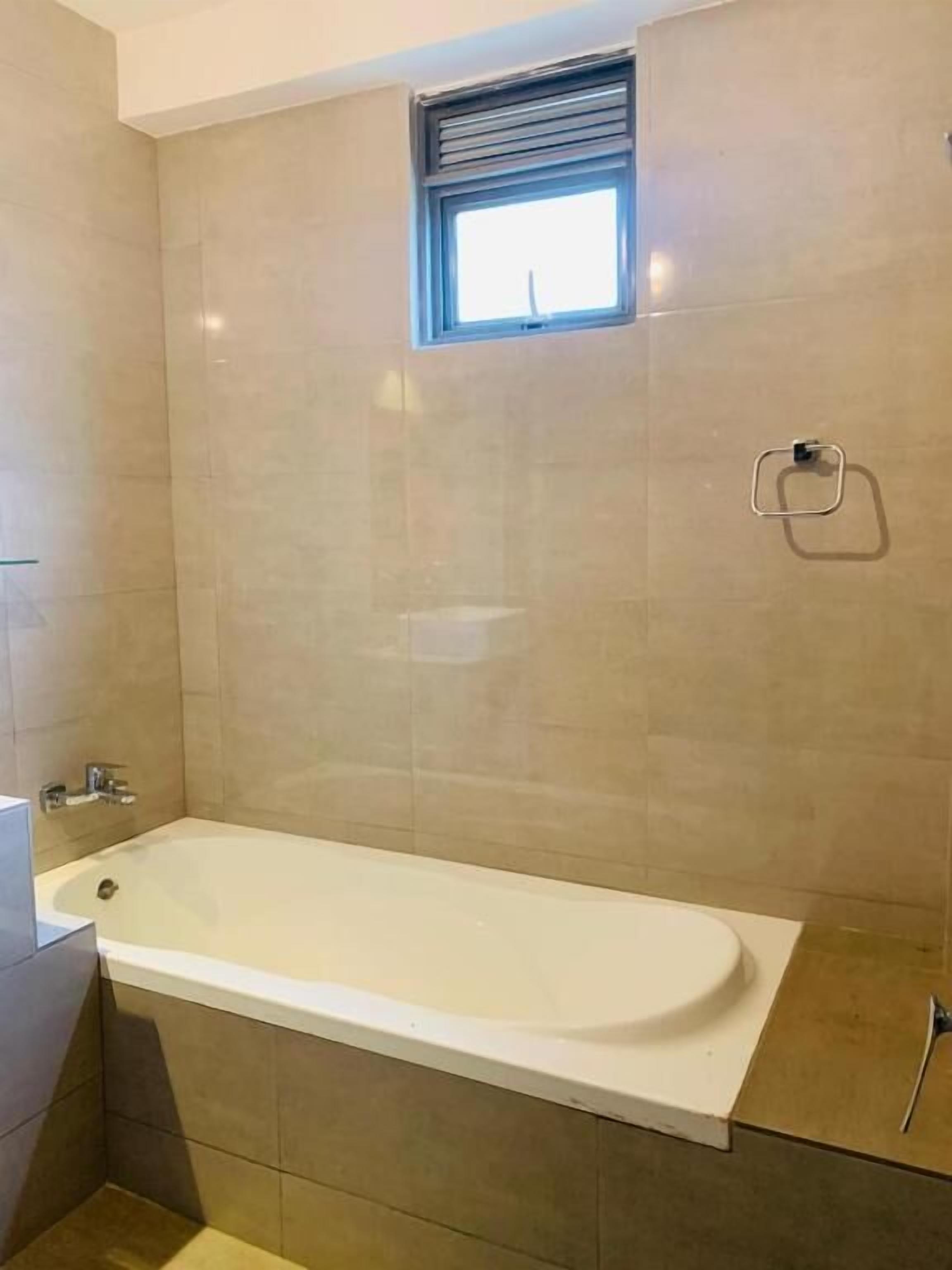 A bathroom with a bathtub, a window, and a towel rack.