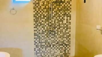 Une salle de bain avec un mur de douche à carreaux, une baignoire et une fenêtre.