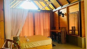 A wooden cabin room with a bed, a table, and a chair.