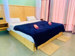 A single bed with a wooden headboard, white bedding, and two rolled towels. - Happy Sky Ella (Ella)