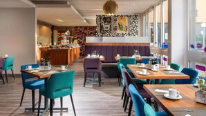A modern dining area with wooden tables and teal chairs, a central bar area, and a patterned wall. - 3 Person Holiday Park Home in Berlin (Berlin)