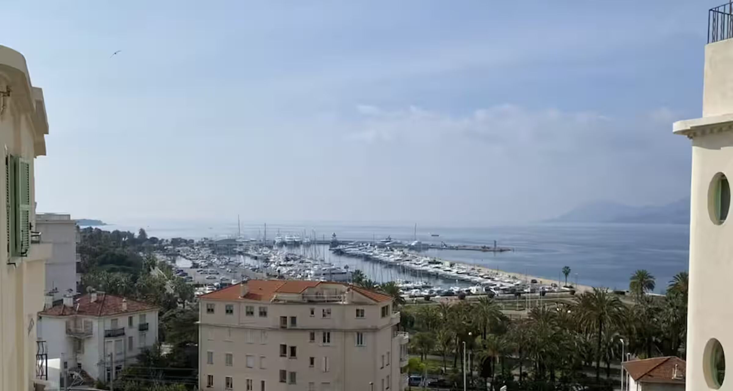 Un paysage urbain côtier avec des bâtiments, un port de plaisance et un ciel dégagé.
