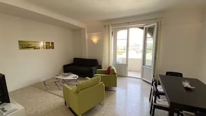 Ein Wohnzimmer mit einer Couch, einem kleinen Tisch und einem Essbereich mit Tisch und Stühlen.