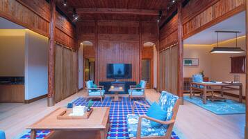 Un salón espacioso con un televisor de pantalla plana grande, muebles de madera y un suelo estampado.