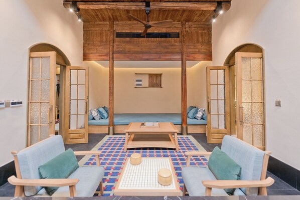 A room with a wooden ceiling, a central seating area with a table, and two doors with frosted glass panels.