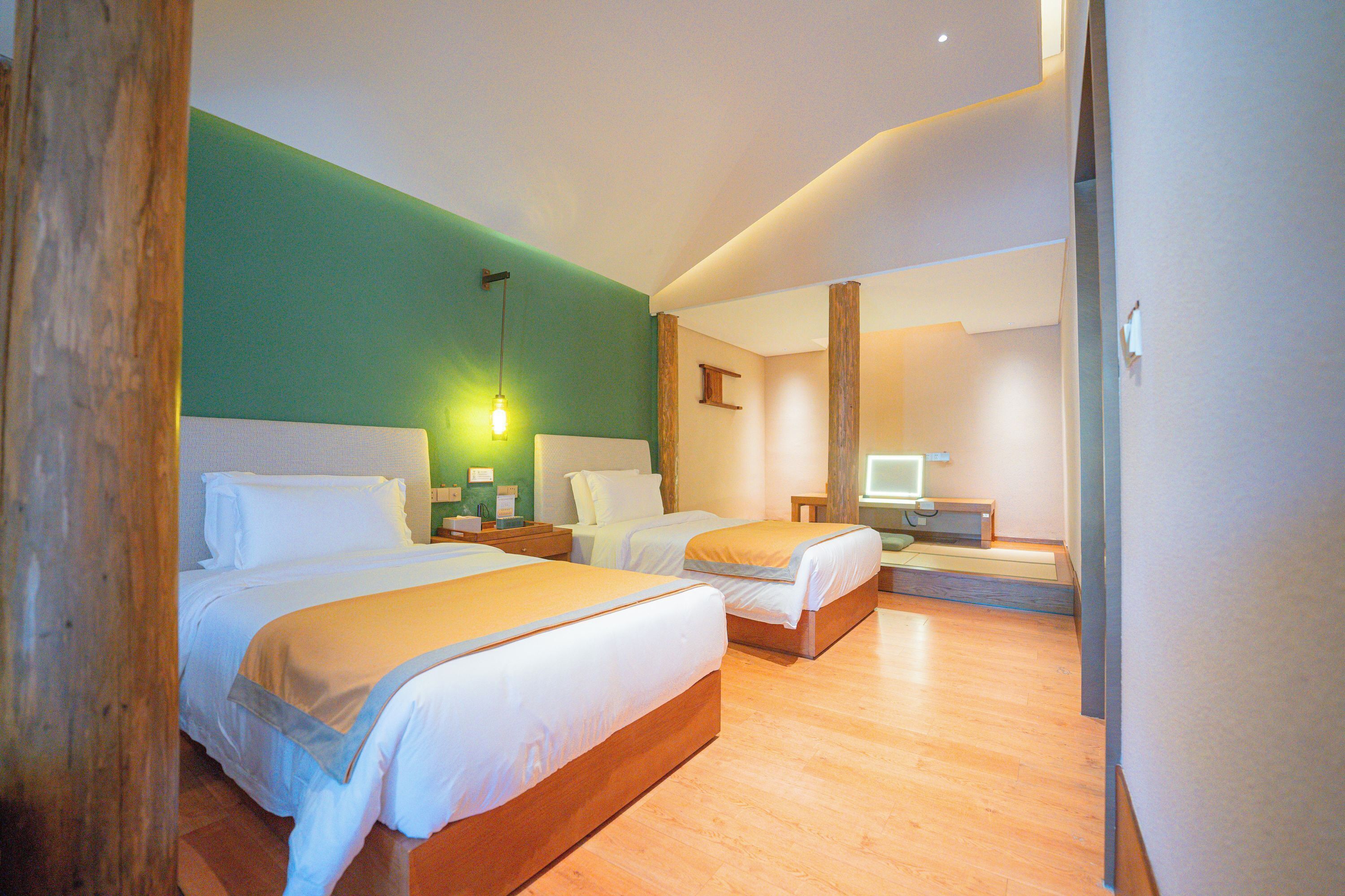 Une chambre d’hôtel avec deux lits, un bureau, une chaise, une lampe et un téléviseur.
