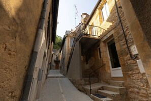 A narrow alleyway with stone buildings, a staircase, and a metal railing. - Hostcare - Le Secret Sarladais – Downtown (Sarlat-la-Canéda)
