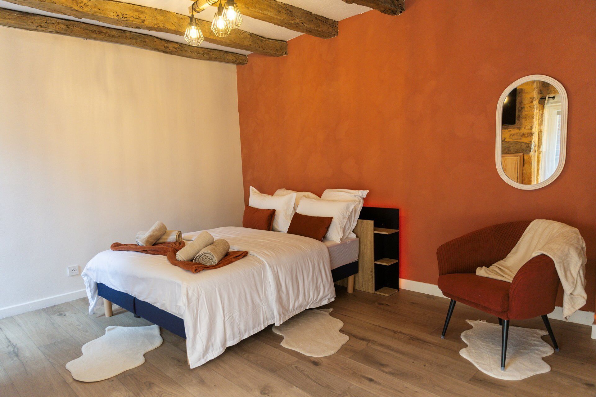 Un dormitorio con cama, una silla, un espejo y techo de madera.