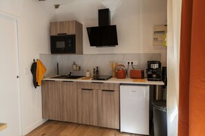 Una cuina compacta amb microones, cafetera i nevera petita.