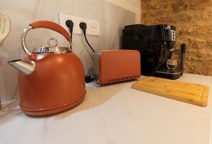 A kitchen with a kettle, a toaster, and a coffee maker on a countertop. - Hostcare - Le Secret Sarladais – Downtown (Sarlat-la-Canéda)