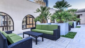 A rooftop terrace with outdoor furniture, palm trees, and a view of a tall building. - Cozy, stylish and vibrant Downtown Los Angeles home available for Sept 1-30 (Los Angeles)