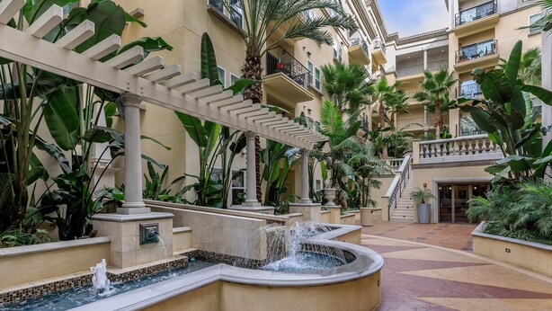 A courtyard with a fountain, palm trees, and a building with balconies. - Cozy, stylish and vibrant Downtown Los Angeles home available for Sept 1-30 (Los Angeles)
