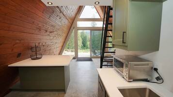 A kitchen with a wooden ceiling, a toaster, and a window overlooking greenery.