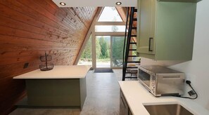 Una cocina con techo de madera, un tostador y ventana con vistas a follaje.
