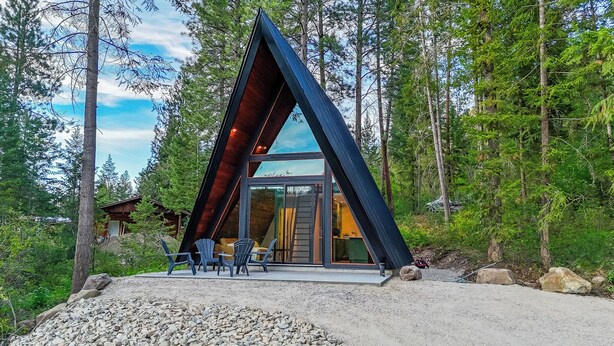 Un edificio moderno de forma triangular con entrada de vidrio, rodeado de zona boscosa.