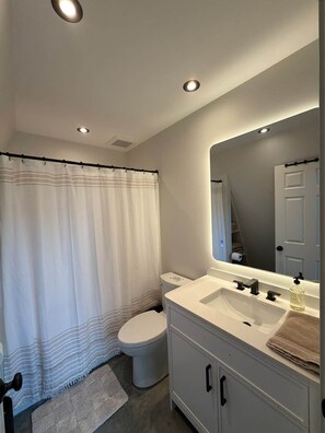 A modern bathroom with a toilet, sink, and shower curtain.