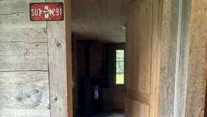 A wooden interior with a door leading to a room. A sign with 'SUI-4291' is visible. - La Chotte du Musher, (Champery), by Interhome (Champery)