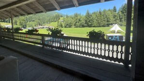 A wooden balcony with a view of a green landscape and a white tent. - La Chotte du Musher, (Champery), by Interhome (Champery)