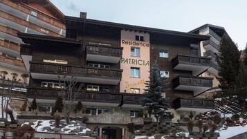 Un hotel a più piani con balconi e un cartello che riporta 'Residence PATRICIA Zermatt'.