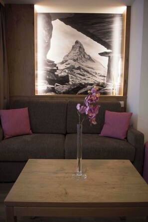 Una stanza con un tavolo di legno, un vaso con fiori e un grande quadro appeso al muro.
