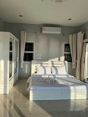 Un dormitorio con cama, cortinas, equipo de aire acondicionado y ventana.