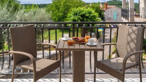 En balkon med fletstole og et bord dækket med morgenmad.
