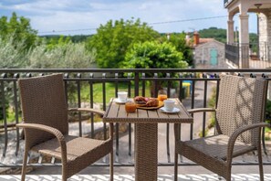 Ein Balkon mit Korbstühlen und einem Tisch, gedeckt für das Frühstück.