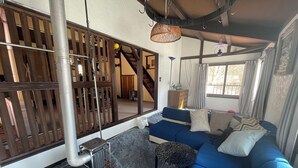 A cozy living room with a blue sofa, a patterned ottoman, and a wood-paneled partition.