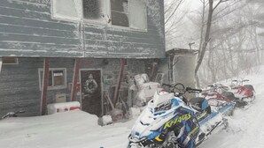 Un bâtiment recouvert de neige, avec une motoneige garée devant.