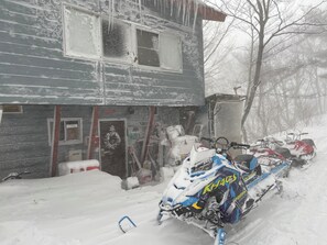 A snow-covered building with a snowmobile parked in front.