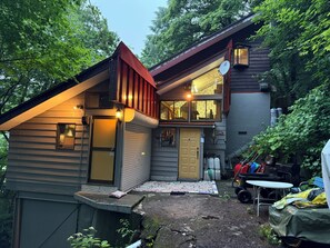 A two-story house with a visible garage door, a satellite dish, and a small outdoor seating area.