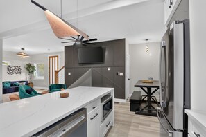 Eine moderne Küche mit einer großen Kochinsel, eingebauten Geräten und einem Flachbildfernseher.