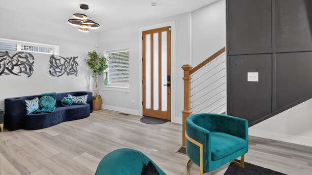 Ein modernes Wohnzimmer mit einem dunkelblauen Sofa, türkisfarbenen Sesseln und einer Holztreppe.