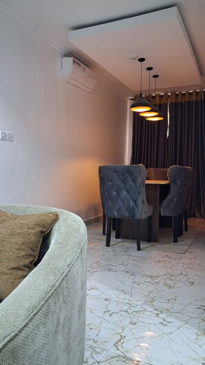 A dining area with a table and chairs, a ceiling light fixture, and an air conditioning unit. - Lovely Spacious 3-bedroom apartment with AC in awesome Lagos, 15min from Airport (Lagos)