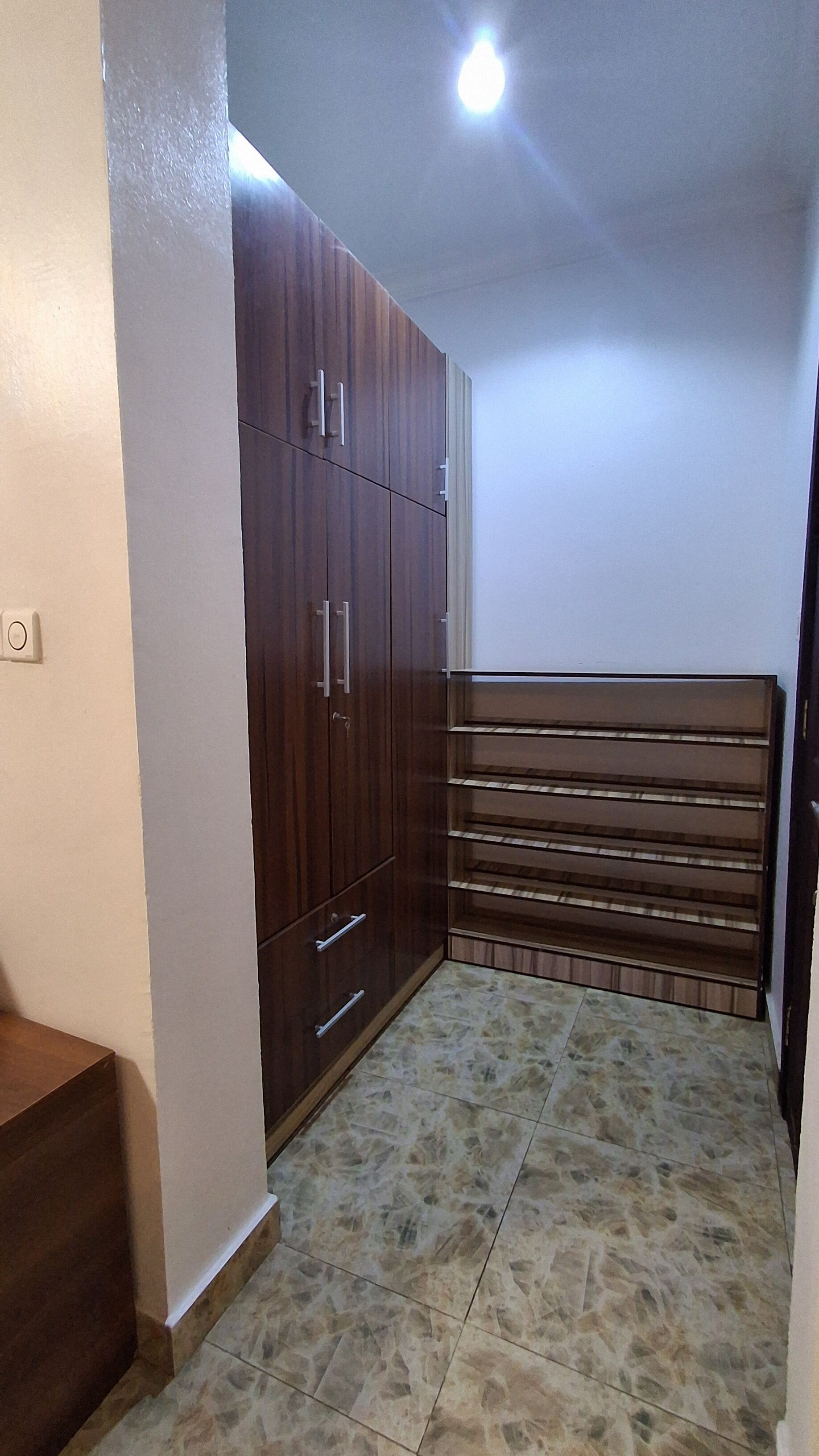 A room with a wardrobe, a bench, and a tiled floor.