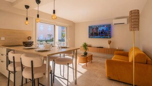 A modern kitchen with a dining area, a sofa, and a TV mounted on the wall. - BRAND-NEW APARTMENT - SWIMMING POOL - PRIVATE PARKING - WALKING DISTANCE TO THE TOWN CENTRE AND... (STE MAXIME)