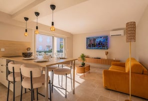 Eine moderne Küche mit Essbereich, einer Couch und einem an der Wand befestigten Fernseher.