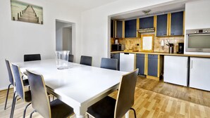 Uma cozinha moderna com uma mesa de jantar branca, cadeiras e um quadro na parede.