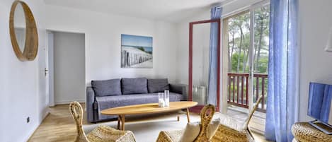 Una sala de estar con sofá, mesa de centro y una silla de mimbre.