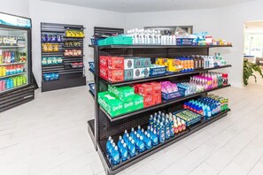 Passís de begudes amb estantes plenes de refrescos, sucs i productes de neteja.