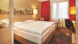 A hotel room with a large bed, a desk with a chair, a lamp, and a painting on the wall. - 2 Person Holiday Park Home in Hannover (Hannover)