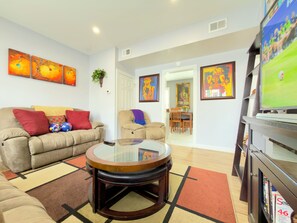 A living room with a sofa, a coffee table, a TV, and a bookshelf.