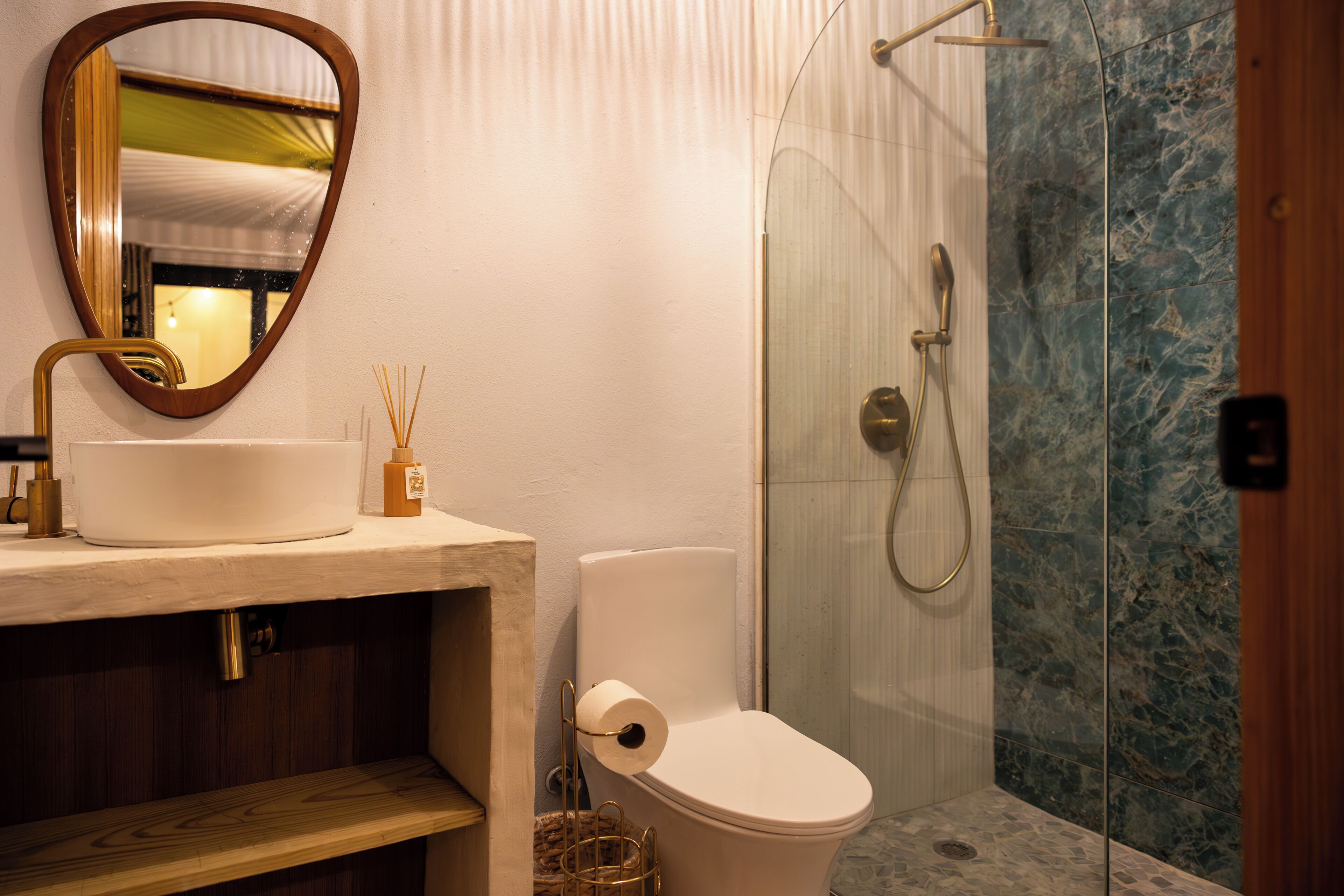 A bathroom with a toilet, sink, mirror, and shower.
