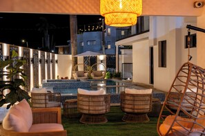 A pool area with wicker furniture and a hanging light fixture.
