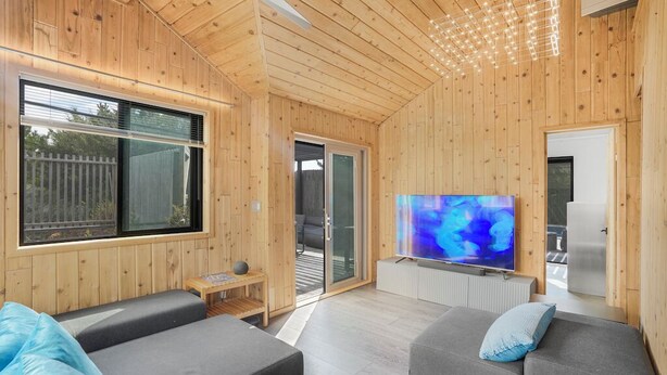 Un salon moderne avec des murs en bois, un téléviseur à écran plat et un canapé.