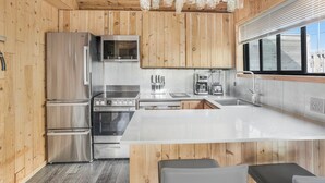 Une cuisine moderne avec des murs en bois, des appareils en acier inoxydable et un grand îlot central.
