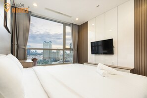 Una camera d'albergo con un letto grande, una TV a parete e vista sulla città attraverso la finestra.