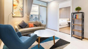 Una sala de estar moderna con un sofá, un sillón y una mesa de centro, una estantería y un ventanal con vistas.