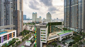 Un edificio de gran altura con varios pisos, rodeado de otros edificios altos, y un cielo despejado.