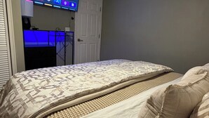 A bedroom with a bed, a television mounted on the wall, and a door. -  Modern 2BR • 10 Min to Sky Harbor & Downtown (Phoenix)